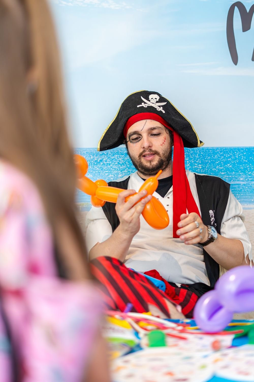 Pirate-costumed entertainer making a balloon animal for a child
