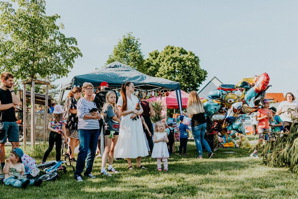 Families gathered outdoors at a community event with balloon decorations